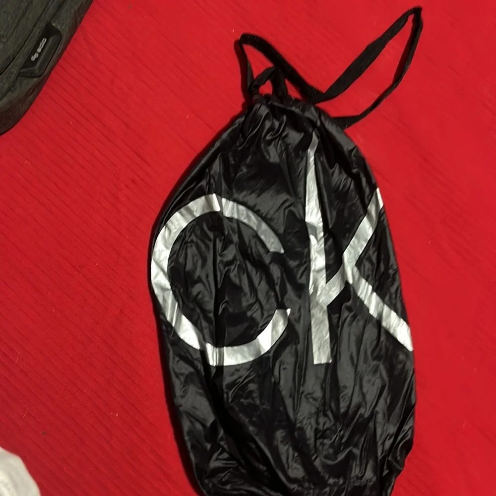CK black draw string bag, used but great condition. Black and silver 12” x 5”
